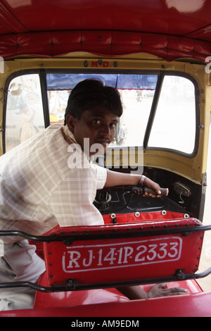 Un chauffeur montre l'intérieur de son autopousse à Jaipur, en Inde. Le pousse-pousse automatique est décoré avec un intérieur rouge élégant. Banque D'Images