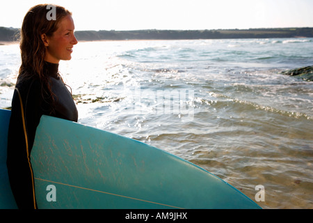 Femme debout avec un surfboard smiling. Banque D'Images