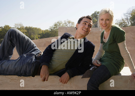Couple sitting outdoors smiling avec la femme tenant une caméra. Banque D'Images