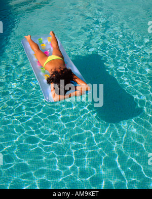 Femme flottant dans une piscine sur son ventre. Banque D'Images