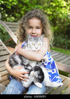 Young Girl outdoors smiling avec un chat sur ses genoux. Banque D'Images