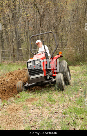 L'homme sur petit tracteur laboure un petit morceau de terre en jachère sur batterie. spécialiste Banque D'Images