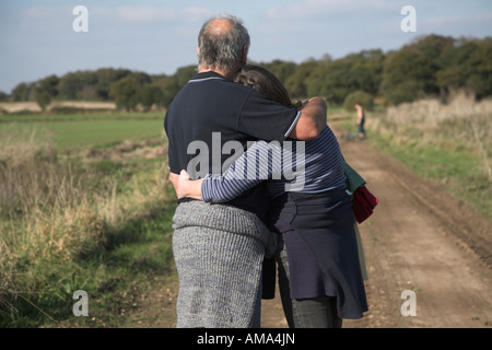 Couple d'âge moyen pause sur pied pour un câlin à l'opposé de l'appareil photo avec enfant à distance Banque D'Images