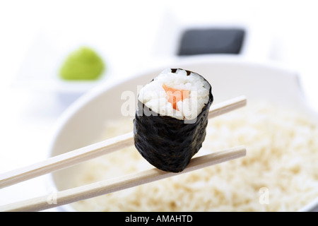 Maki Sushi avec des baguettes au-dessus du bol de riz, close-up Banque D'Images