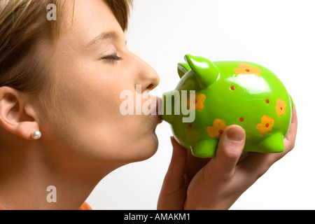 Young woman kissing piggy bank Banque D'Images