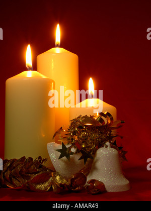 Trois cloches de Noël avec DES BOUGIES DE L'église et les cônes de sapin d'or sur fond rouge foncé Banque D'Images