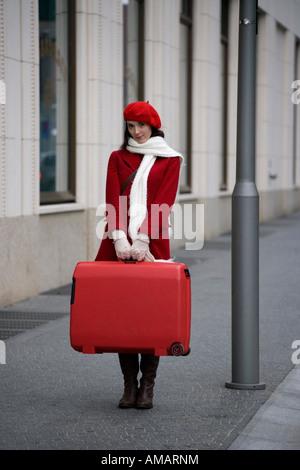 Une femme debout dans la rue avec une valise Banque D'Images