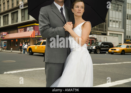 Une femme et un homme debout sous un parapluie sur une rue de Manhattan Banque D'Images