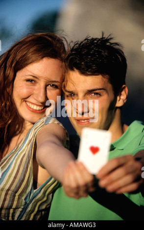 Jeune couple montrant Ace of Hearts, se concentrer sur deux à l'arrière-plan, close-up Banque D'Images