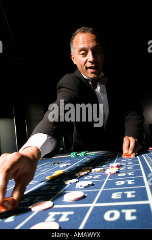 Bien habillé man placing bet at roulette table Banque D'Images