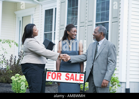Middle-aged man shaking hand avec un agent immobilier et d'une femme d'âge moyen en le regardant Banque D'Images