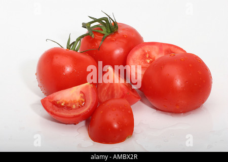 Tomates cerises rouges mûres entières et en morceaux avec des gouttes d'eau section transversale du dessus personne isolé découpe découpée sur la table blanche haute résolution Banque D'Images