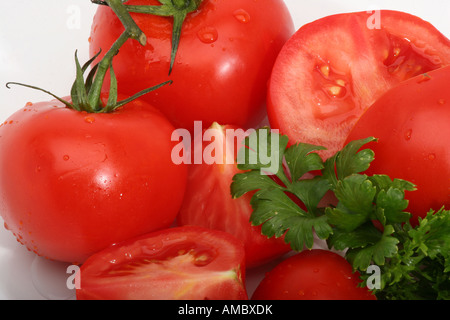 Gros plan de tomates rouges mûres biologiques entières et en morceaux avec des gouttes d'eau coupe transversale du dessus de personne sur la table haute résolution Banque D'Images