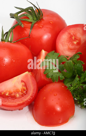 Gros plan de tomates rouges mûres biologiques entières et en morceaux avec des gouttes d'eau coupe transversale du dessus de personne sur la table haute résolution Banque D'Images