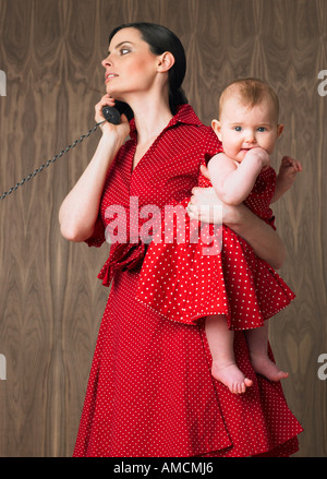 Woman Holding Baby lors de l'utilisation de téléphone Banque D'Images