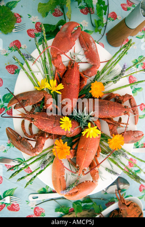 Une vue aérienne d'un plat de fruits de mer somptueux de langoustines, araignées de mer et homard, décorée avec un assortiment de fleurs sur une table Banque D'Images