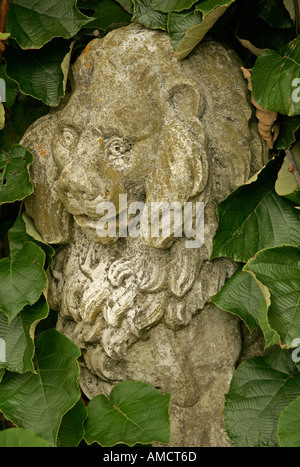 Statue de pierre d'un lion en partie caché dans le sous-bois Banque D'Images