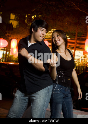 Couple listening to mp3 player outdoors dancing and smiling Banque D'Images