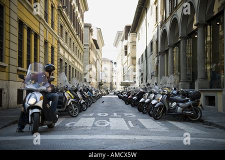 Sur l'homme à la moto de retour à rangées de motos en stationnement sur rue avec de vieux bâtiments Banque D'Images