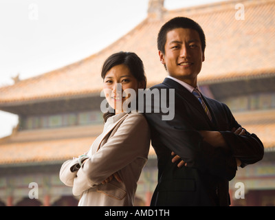 Businessman and woman standing with arms crossed et dos avec pagoda en arrière-plan Banque D'Images