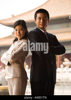Businessman and woman standing with arms crossed et dos avec pagoda en arrière-plan Banque D'Images