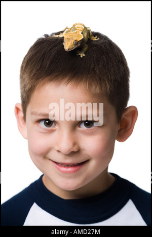 Gros plan du garçon avec lizard on head smiling Banque D'Images