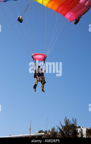 Tandem saut en parachute au-dessus de toits colorés avec against blue sky Banque D'Images