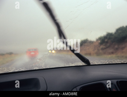 La conduite dans la pluie avec de l'essuie-comme vu par pare-brise de la voiture à l'intérieur Banque D'Images