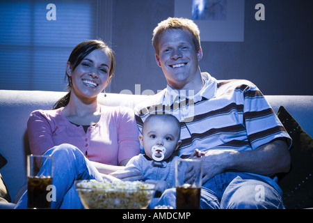 Couple on sofa with baby smiling Banque D'Images