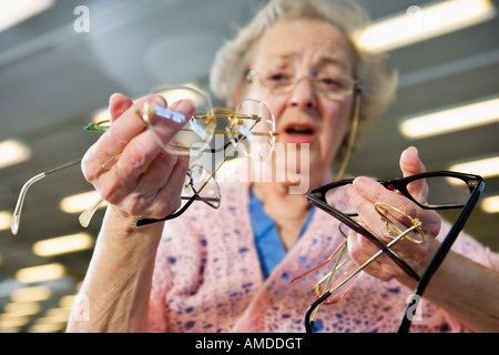 Low angle view of a confused senior woman holding lunettes. Banque D'Images
