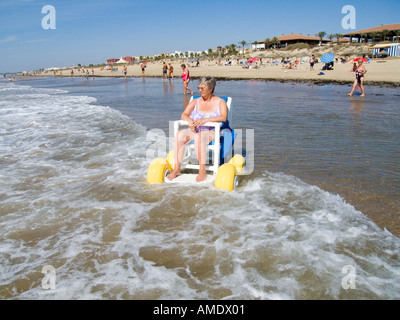 Une mobilité tourist en utilisant un fauteuil roulant de plage avec de grandes roues en plastique Espagne Banque D'Images