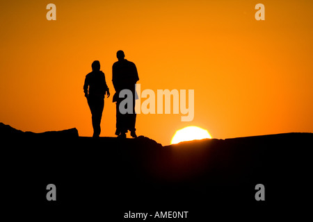 Couple walking on rocks au coucher du soleil Banque D'Images