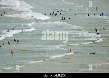 Plusieurs surfeurs de Cornouailles en attente sur la houle de la mer comme les vagues blanc casser sur open beach Banque D'Images