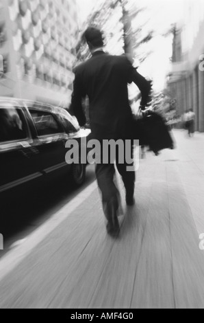Vue arrière de Businessman Walking On Street Carrying Briefcase Banque D'Images