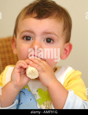 Un bébé mange une banane Banque D'Images