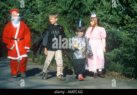 Quatre enfants habillés en costumes différents marcher le long d'une rue au carnaval Banque D'Images