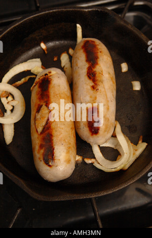 La cuisson des saucisses de porc avec l'oignon dans une poêle Banque D'Images