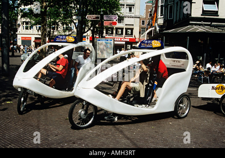 Wieler taxis et les touristes en attente dans un carré, Amsterdam, Pays-Bas Banque D'Images