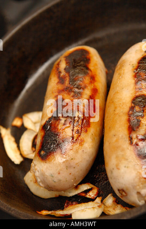 La cuisson des saucisses de porc avec l'oignon dans une poêle Banque D'Images