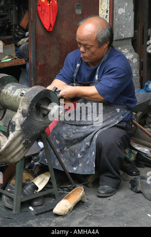 Un vieil homme répare des chaussures dans la rue à Shanghai Chine Banque D'Images