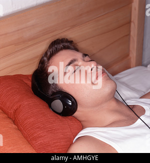 Man Lying on Bed, de l'utilisation des écouteurs Banque D'Images