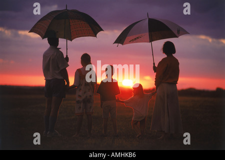 Famille de cinq regardant coucher de soleil africain sous un ciel pluvieux au Zimbabwe Banque D'Images