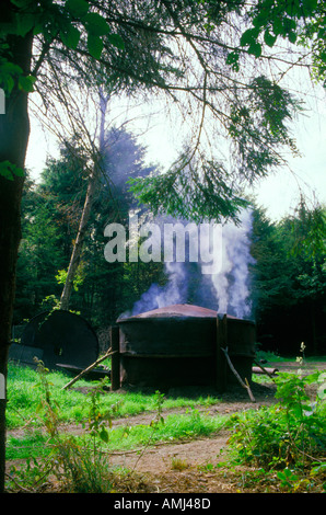 La fabrication de charbon de bois dans une forêt dans le Chiltern Hills avec la fumée de la cheminée avec les fours. Banque D'Images