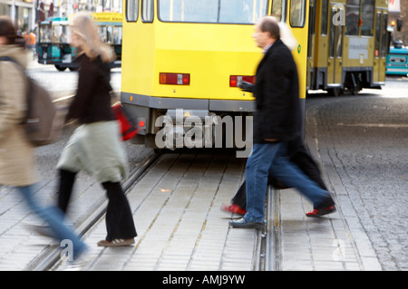 Les gens de marcher à travers les jalonnages derrière déménagement BVG berlin voyager tramway jaune s'Alexanderplatz Berlin Allemagne Banque D'Images