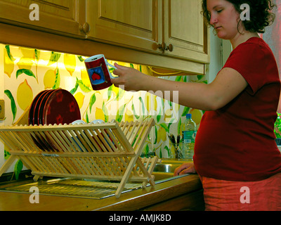 M. PR femme enceinte lave la vaisselle dans la cuisine Banque D'Images
