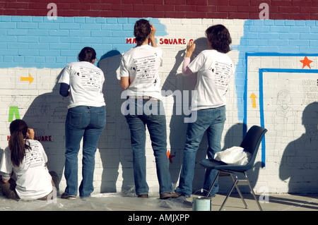 Les bénévoles avec New York Cares une peinture murale sur le côté de l'école PS 33 de Chelsea à New York City Banque D'Images