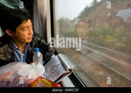 Chinese Man Riding Train en Chine à la recherche des Winow Banque D'Images