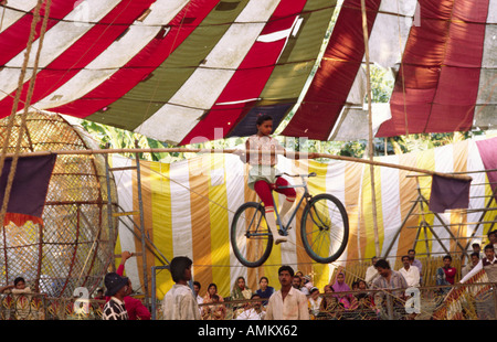 Une jeune femme artiste funambule d'effectuer sur un vélo dans un cirque coloré big top. Le Bangladesh. Asie Banque D'Images