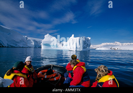 Les touristes de croisière près de l'iceberg à la masse du Zodiaque Banque D'Images