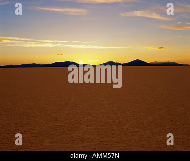 Le soleil se couche derrière les Andes, vu de l'immense croûte de sel du Salar de Uyuni. Banque D'Images
